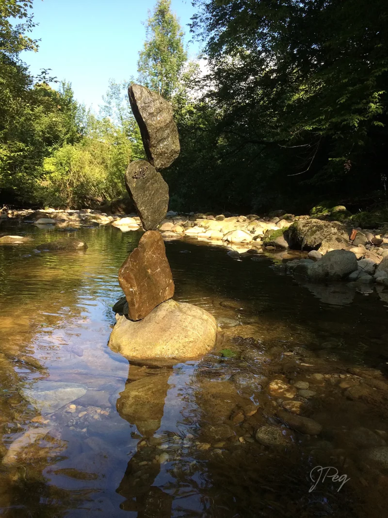 Stacked stones balancing in a clear stream.