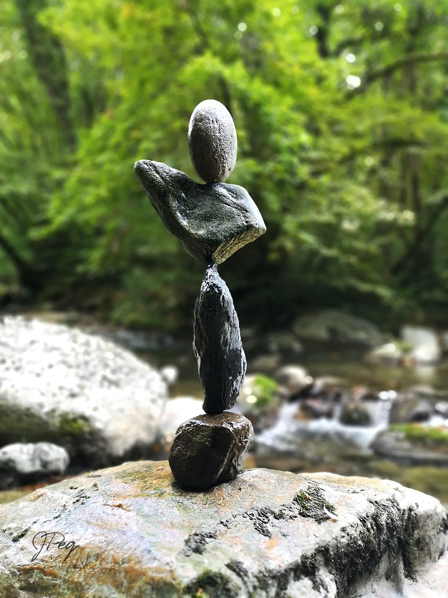 Sculpture en pierre en équilibre sur un rocher au bord d'une rivière.