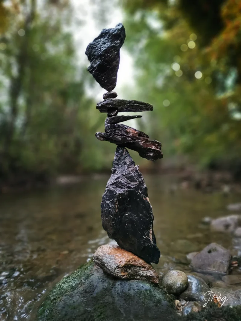 Stacked stones balancing in a serene forest stream.