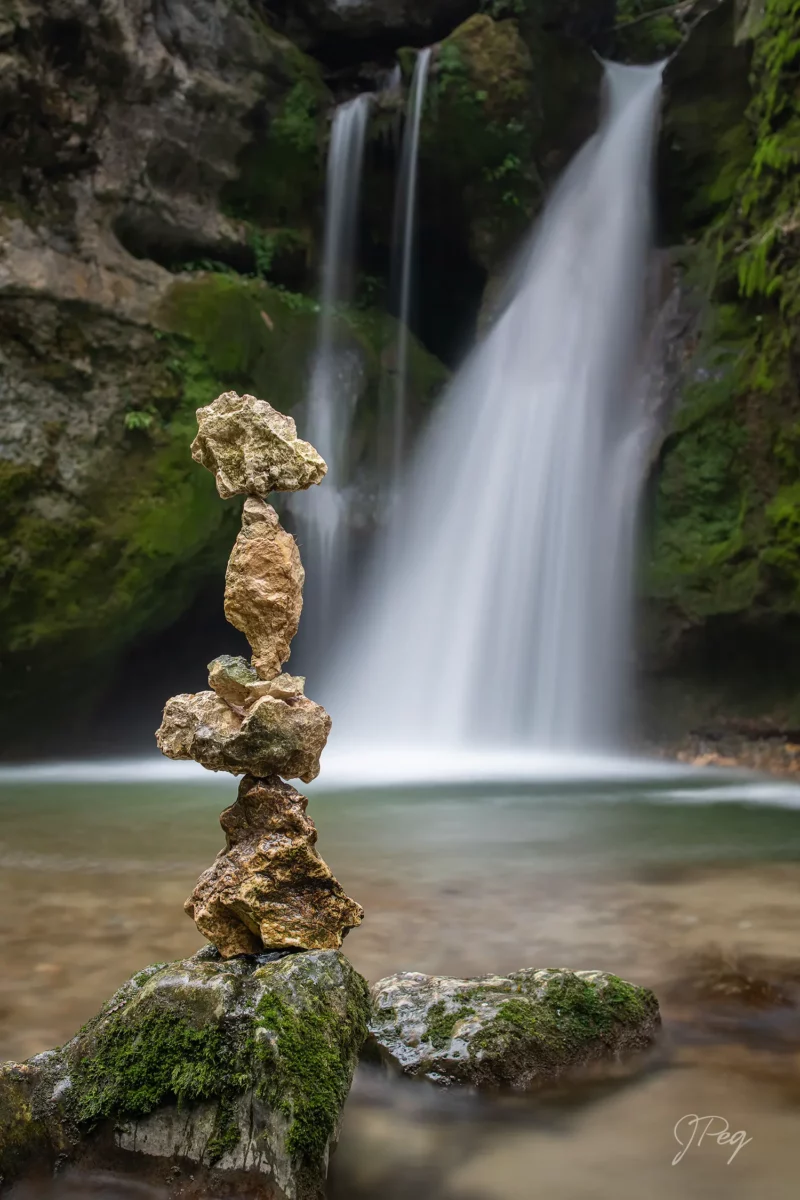 Balanced rocks in front of a waterfall.