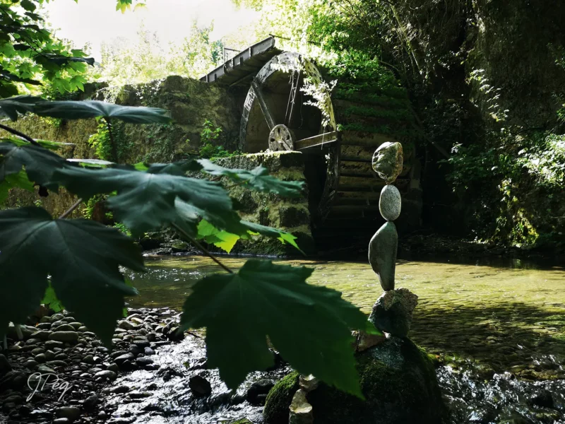 Stone sculpture near water mill and stream.