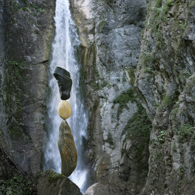 Balanced rocks in front of waterfall in canyon.