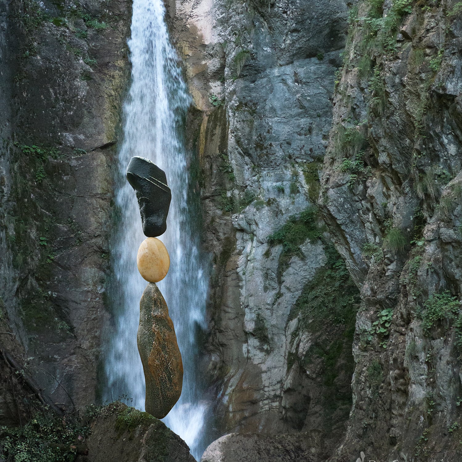 Balanced rocks in front of waterfall in canyon.