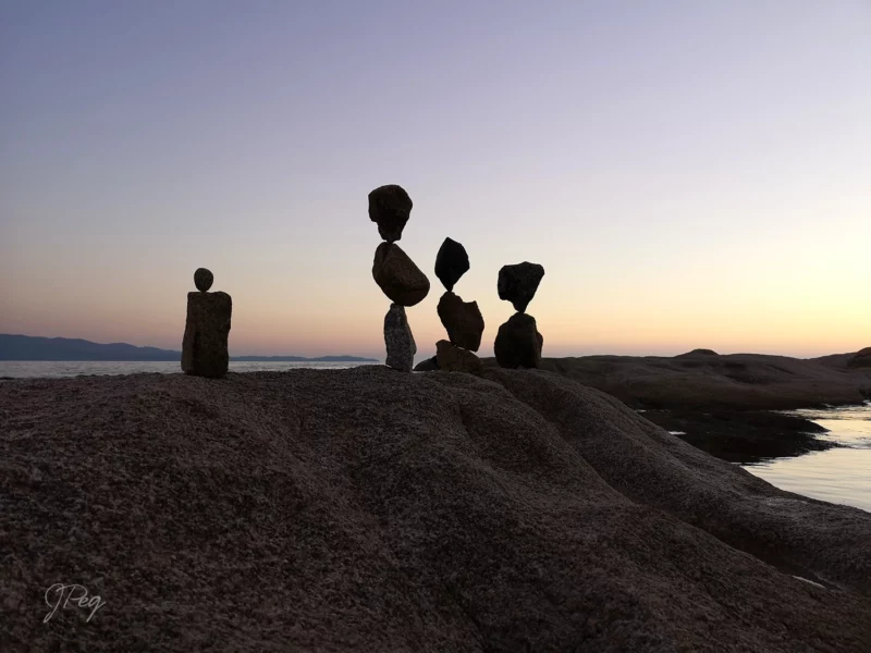 Balanced stones at sunset on rocky shoreline.