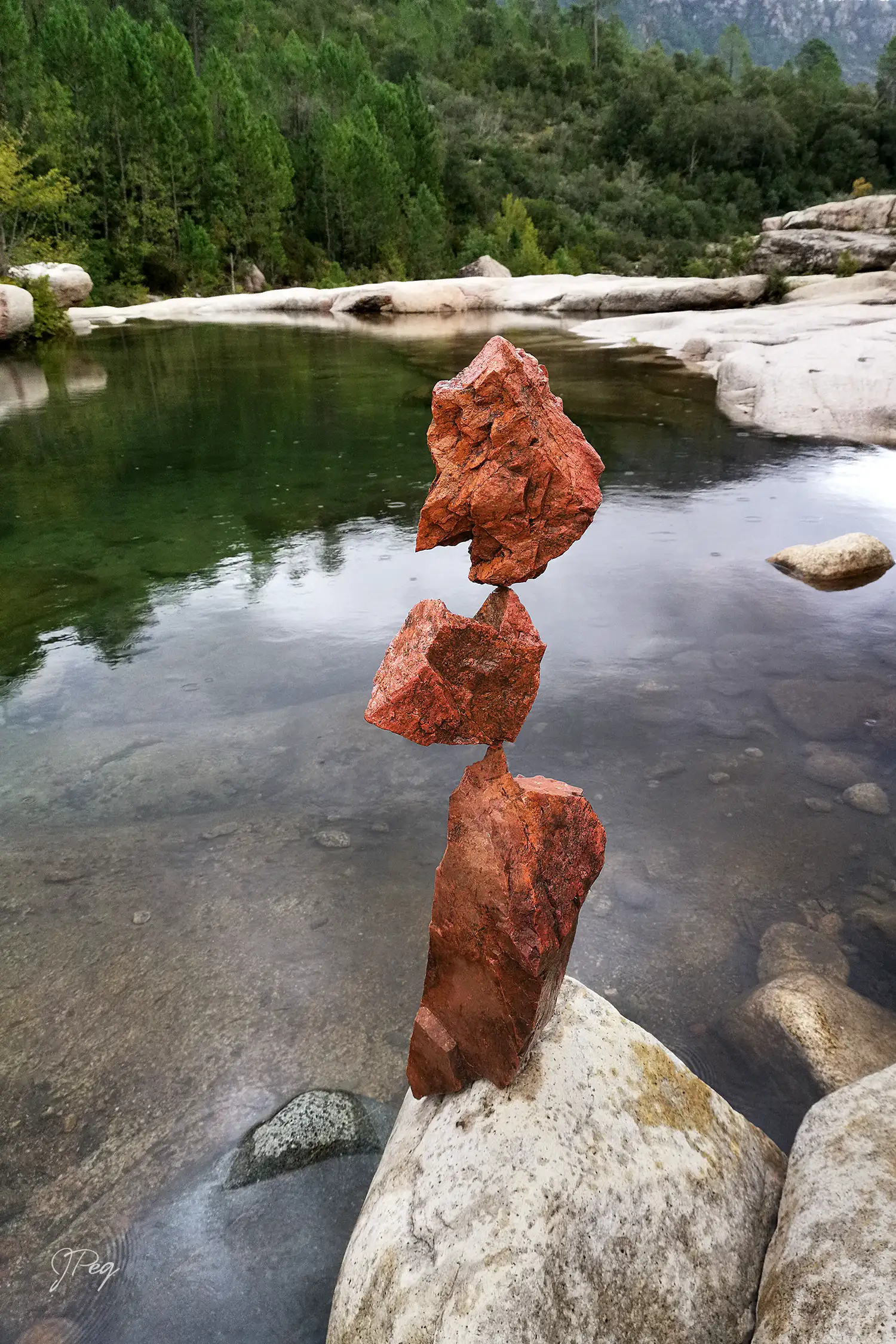 Roches rouges empilées au bord d'une rivière tranquille