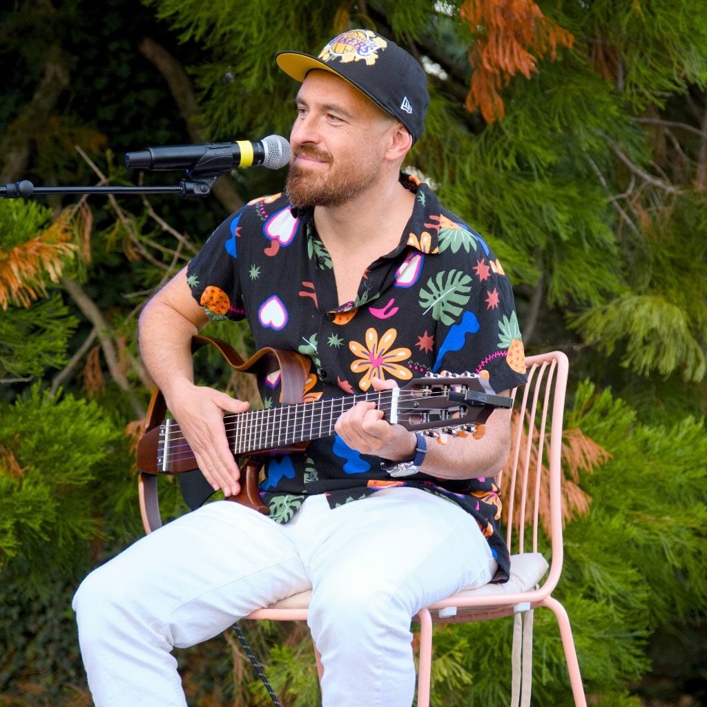 Uomo che suona la chitarra e canta all'aperto.