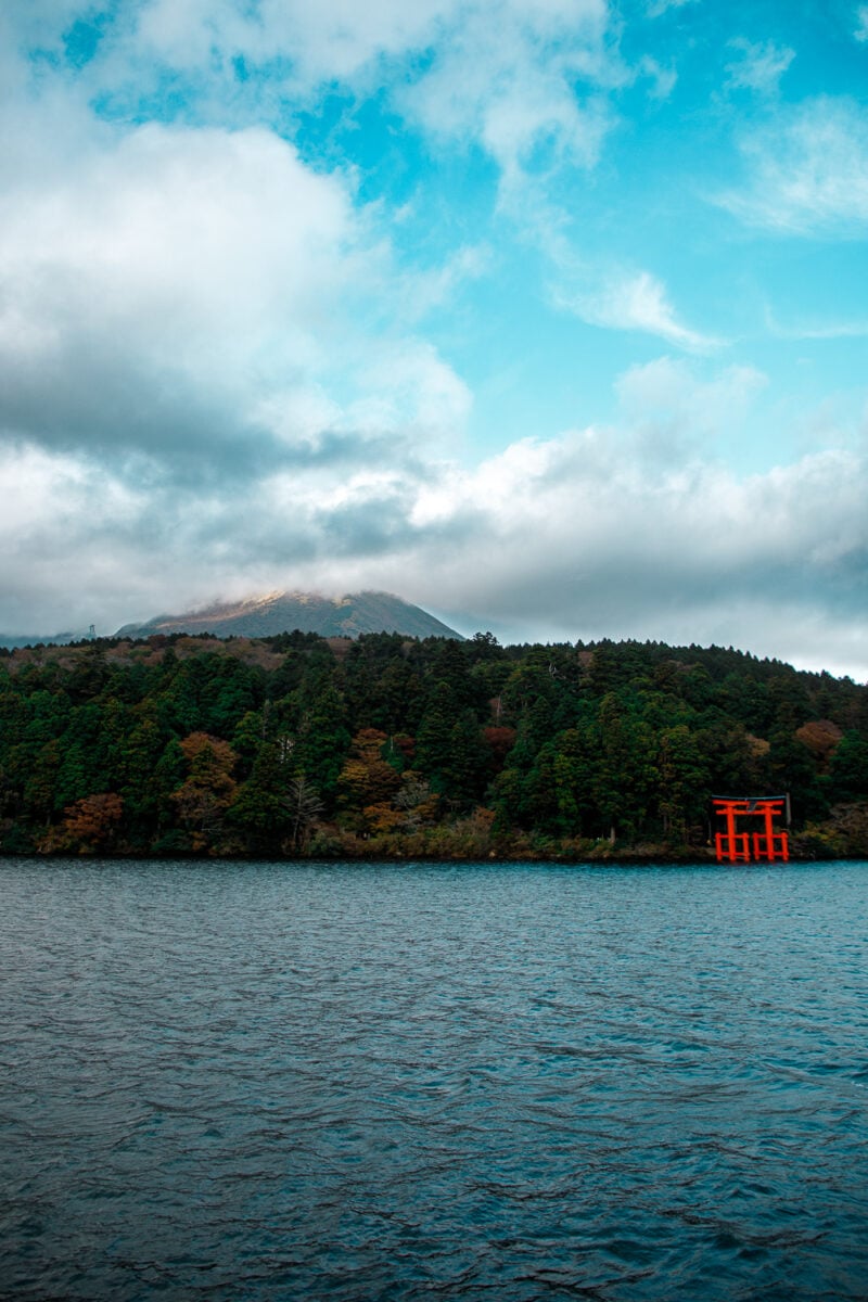 Ashinoko Lake with red Torii gate and mountains.