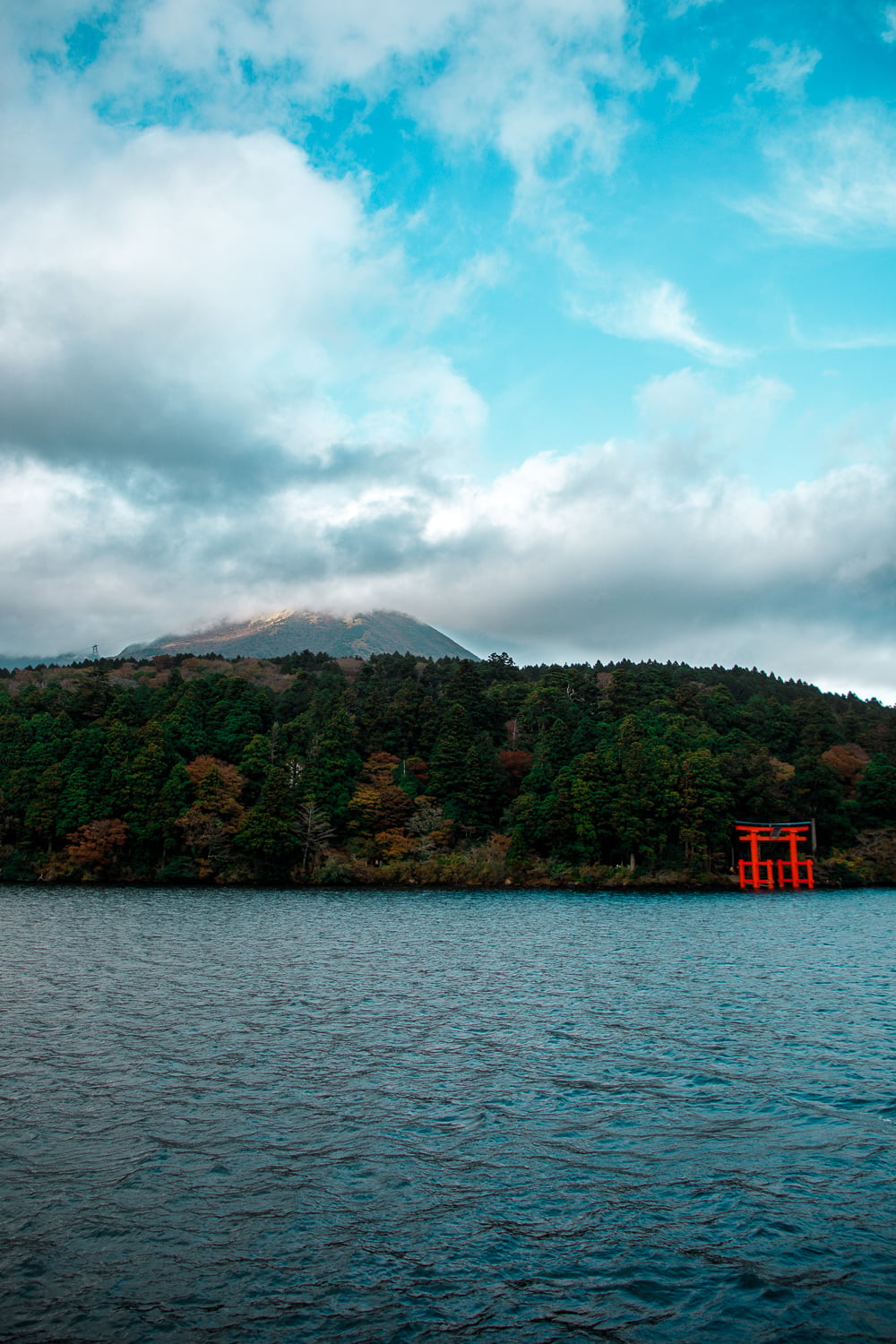 Lac Ashinoko avec porte Torii rouge et montagnes.