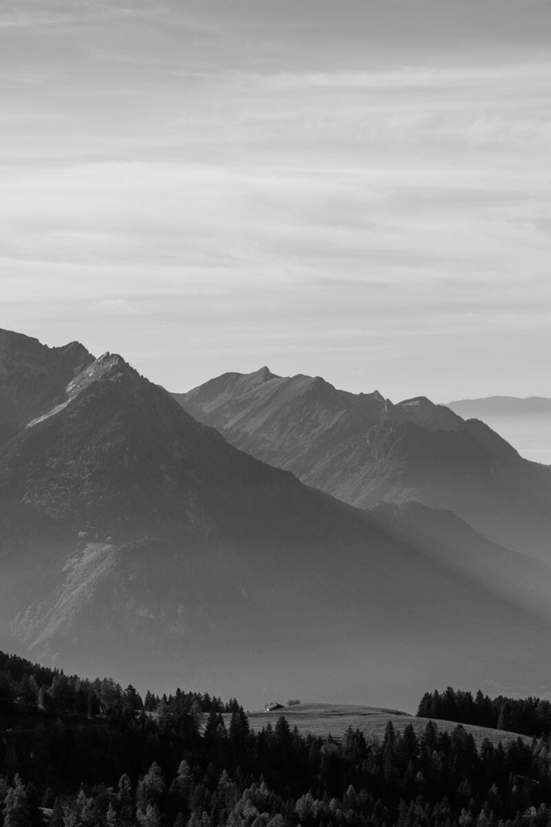 Monochrome mountain landscape with forested slopes.