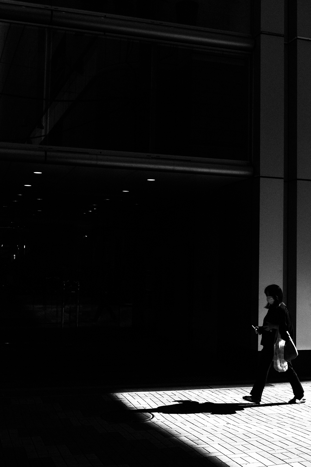 Persona di profilo che cammina alla luce del sole con il cellulare