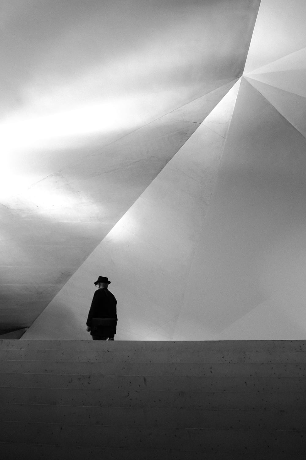 Silhouette d'un homme devant une architecture géométrique moderne.