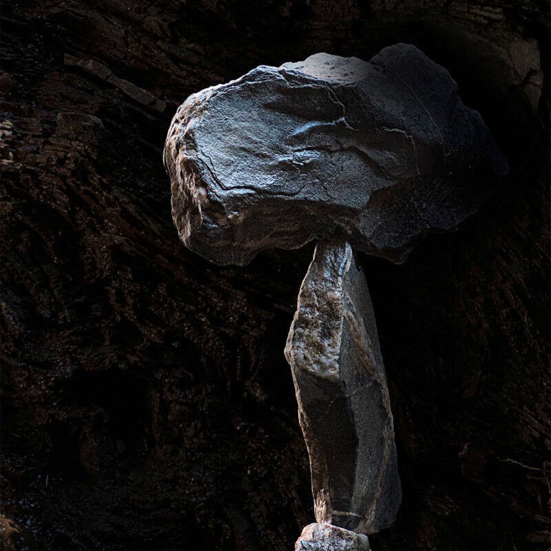 Skulptur eines balancierenden Felsens in einer dunklen Höhle