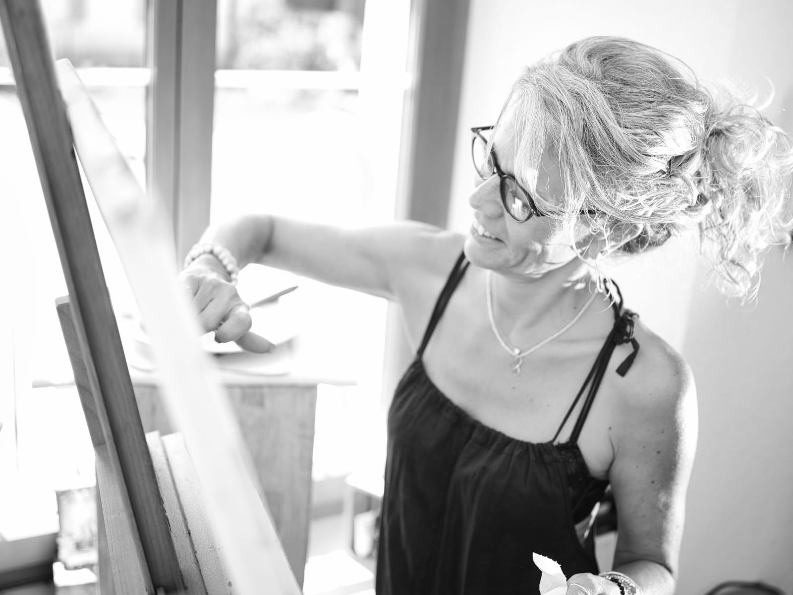 Woman painting on canvas at easel indoors