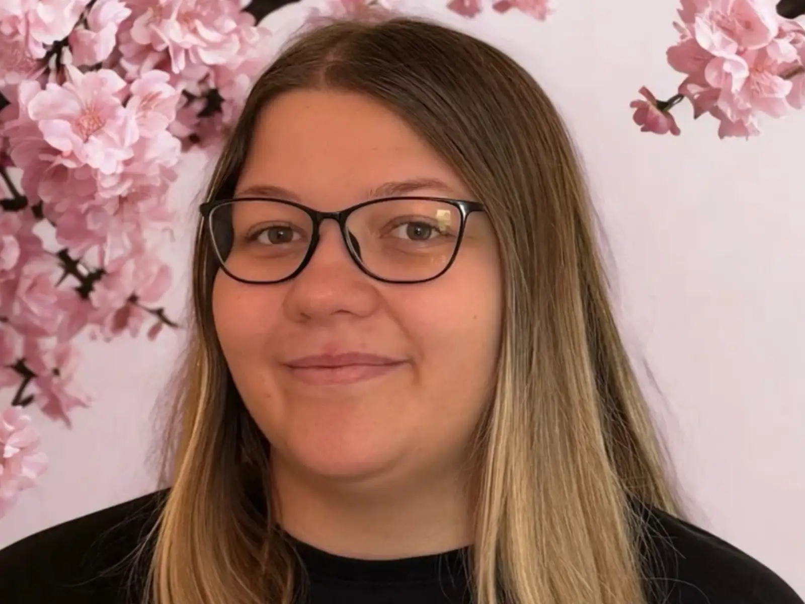 Woman with glasses against pink blossom backdrop