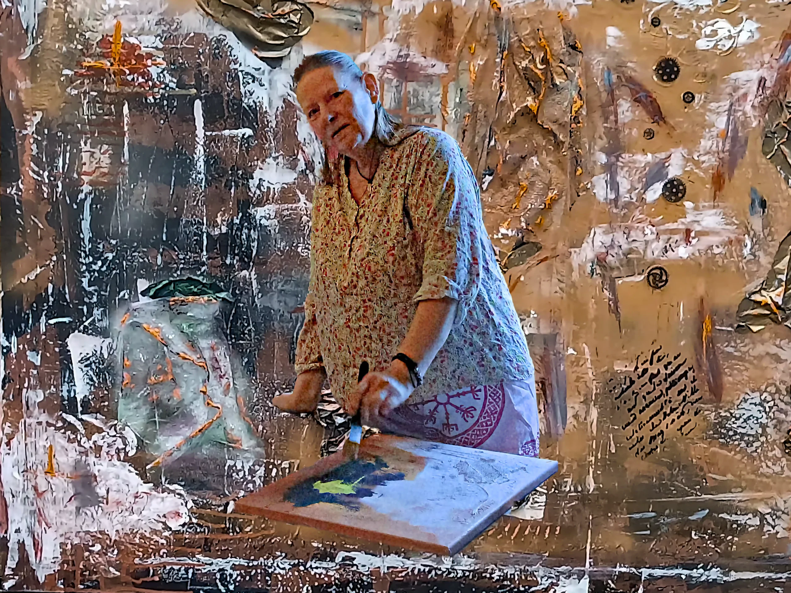 Künstler beim Malen in einem Atelier mit strukturierten Wänden und abstraktem Hintergrund
